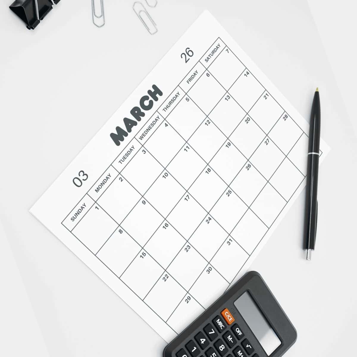 Printable March Calendar March 2026 printable calendar on a desk with pens and a calculator.