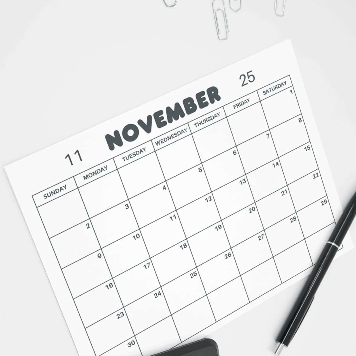 Printable November Calendar November 2025 printable calendar on a des with pens and clips.