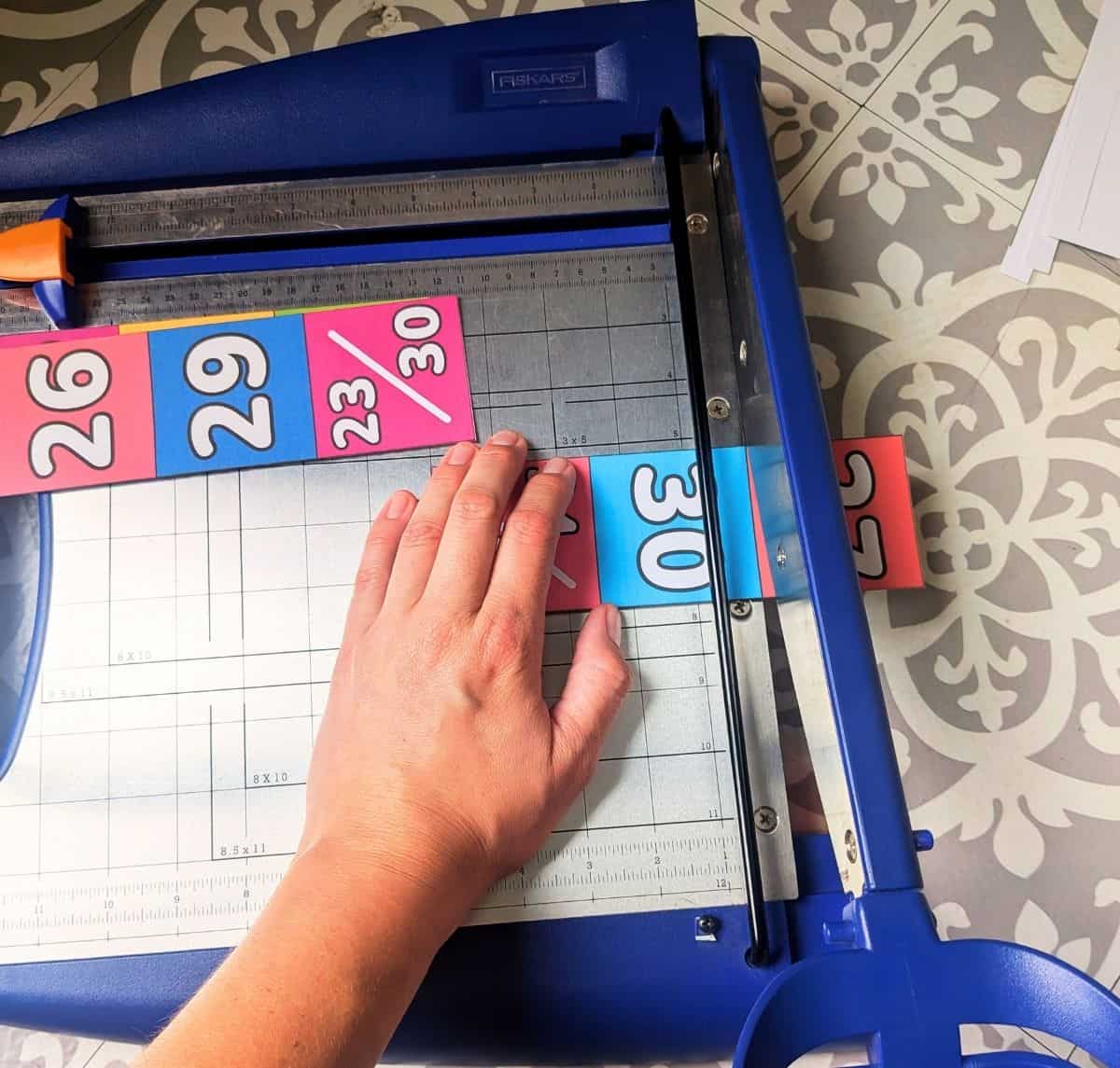 3 Teacher cutting classroom calendar numbers with a paper cutter.